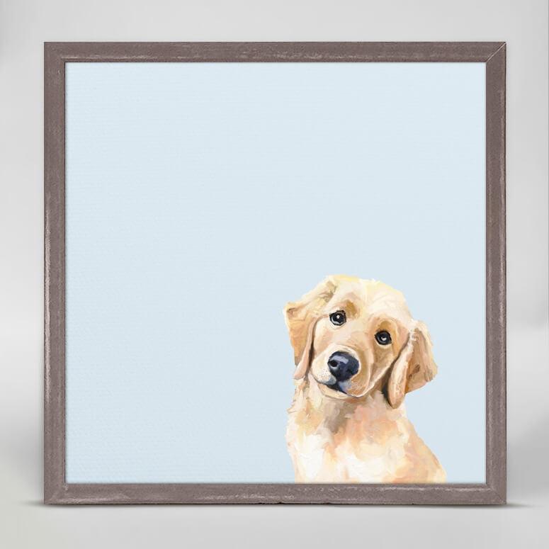 In a light blue background, a print of a yellow puppy with dark eyes and a black nose with its head tilted to the right.