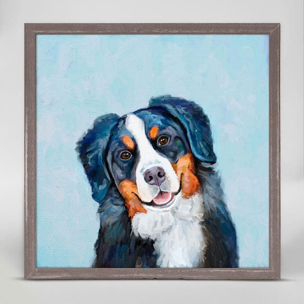 With a blue background, a colored print of a smiling, black dog with white and brown markings on its face.