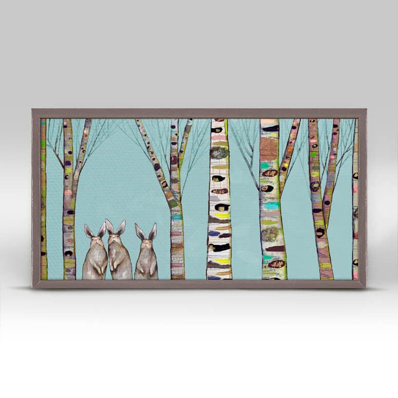 Against a blue background, colorful tree bark stands tall beside three bunnies standing on their hind legs looking forward.
